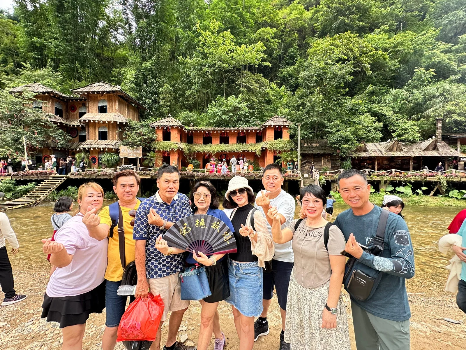 Travellers beside the water with forested hills behind them