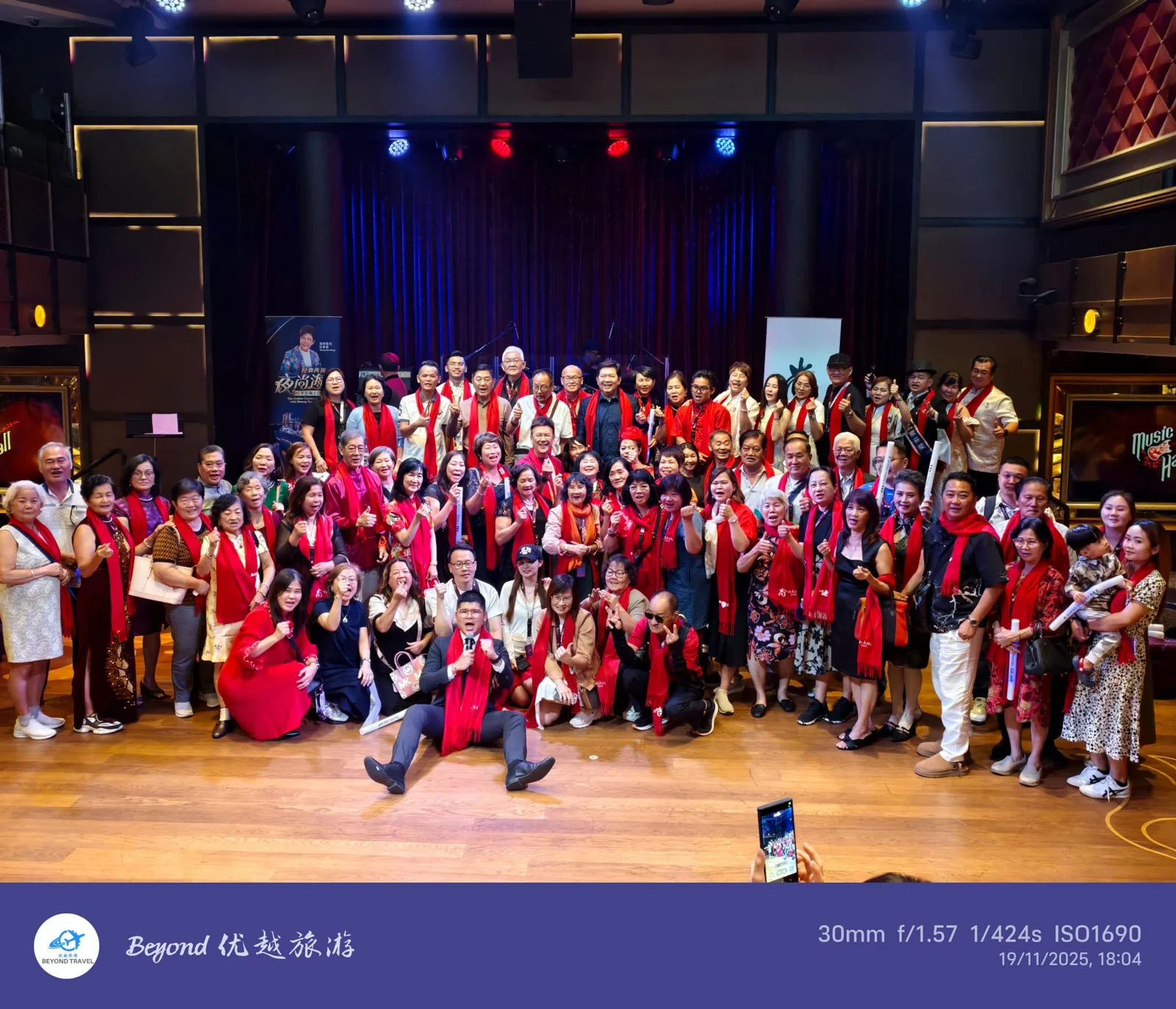 A large travel group posing inside a theatre