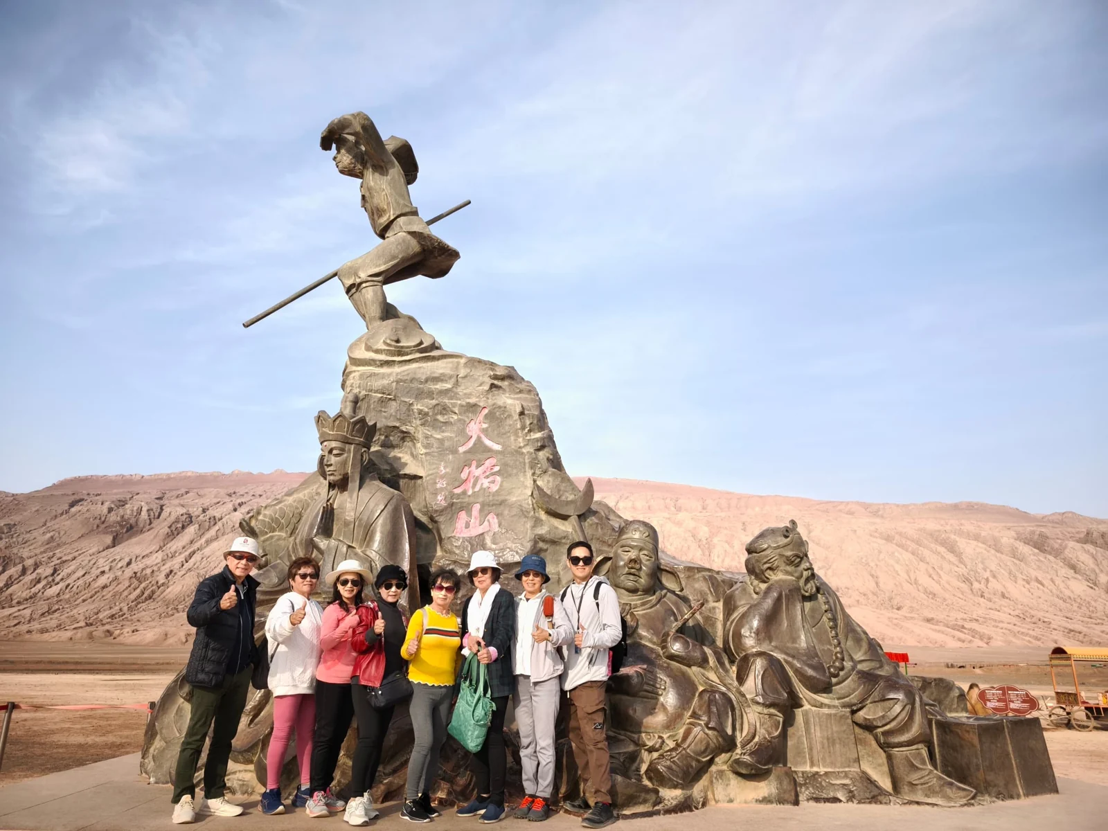 Travellers posing in front of a sculpture